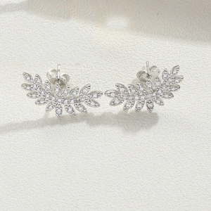 Detail of leaf-shaped silver stud earrings with sparkling cubic zirconia on stone texture