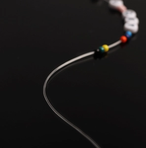 Macro shot of colorful resin beads and letter charms on transparent elastic crystal cord