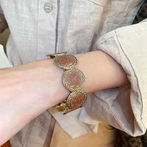 Vintage gold textured bracelet with leopard pattern resin discs on light shirt background