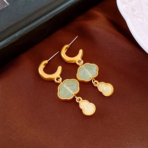 Detail of golden cloud motif and gourd drop earrings on brown silk backdrop
