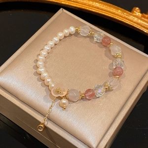 Detail of freshwater pearl bracelet with pink strawberry quartz and floral gold pendant