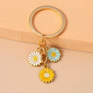 Detail of three colorful enamel daisy pendants on a gold-tone metallic keychain