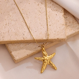 Gold starfish pendant necklace on textured stone slabs with minimalist metal chain link