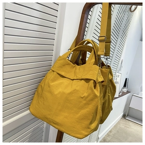 Macro view of a lightweight yellow nylon tote bag hanging on a mirror in a bright room