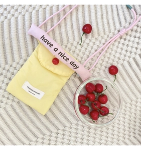Macro shot of yellow fabric phone pouch with pink slogan strap on white knit background