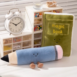 Set di peluche creativi con un libro verde e una matita blu su una scrivania bianca