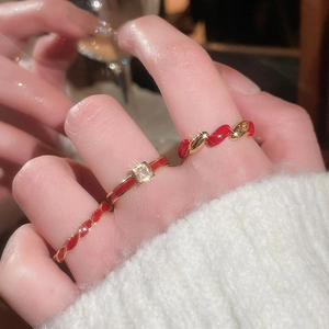 Close-up of three gold-plated red enamel rings set with square zircon on female hand