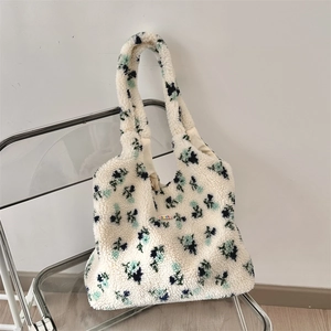 Detail of soft white plush flower tote bag with teal floral patterns on a modern chair