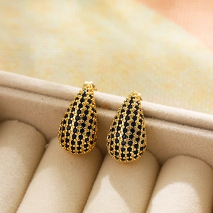 Close-up of gold teardrop earrings with black pavé zircon stones in a jewelry box