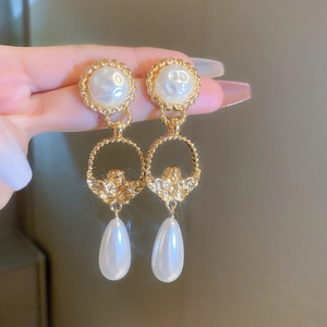 Detail of vintage gold earrings with baroque pearl drops and embossed angel coin charms