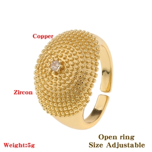 Detail of adjustable gold copper ring featuring grain texture and inlaid zircon stone