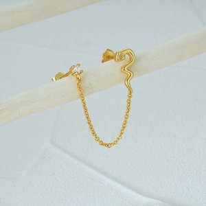 Macro shot of S925 sterling silver snake stud earrings with gold chain and cubic zirconia