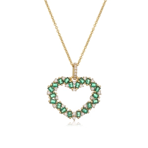 Golden heart necklace with green emerald stones and white diamonds on white backdrop