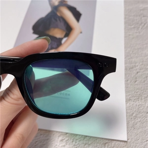 Detail shot of black square sunglasses featuring teal lenses and side metal decorations