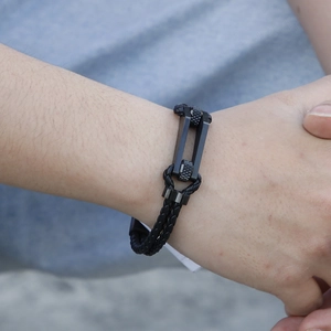 Detail of men's double-layer braided leather bracelet with matte black steel buckle