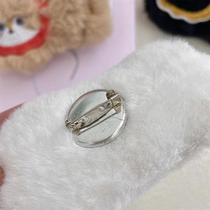 Macro detail of the white plush brooch back with a secure silver metal safety pin