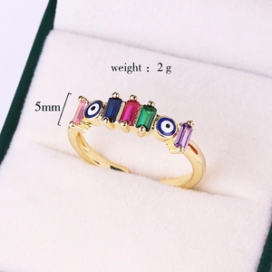 Detail view of gold ring with evil eye motifs and colorful rectangular gemstones