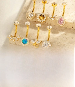 Macro shot of titanium belly button rings with flower and star-shaped zircon charms