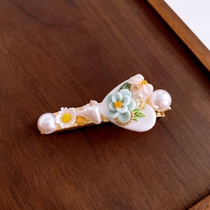 Detailed close-up of a floral hair clip with white daisies, pearls and heart accent