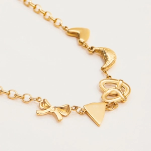 Detail of 18K gold stainless steel bracelet featuring heart, croissant and bow charms
