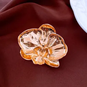 Elegant rose gold orchid flower brooch with hammered texture on a velvet background