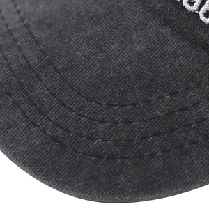 Macro detail of washed black cotton baseball cap brim with parallel stitching