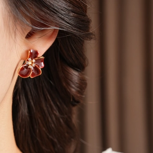 Close-up of red enamel flower stud earring with small crystals on a model's ear