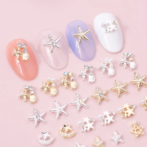 Macro shot of 3D metal star, shell and pearl nail charms on pink background