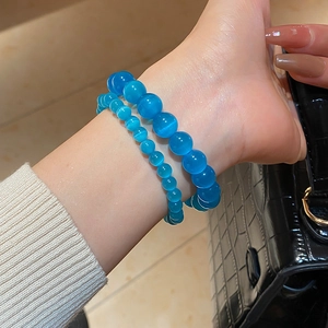 Detail of blue cat eye stone beaded bracelets on wrist with shimmering light effect