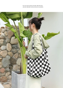 Lifestyle shot of black and white checkered canvas tote bag worn on shoulder