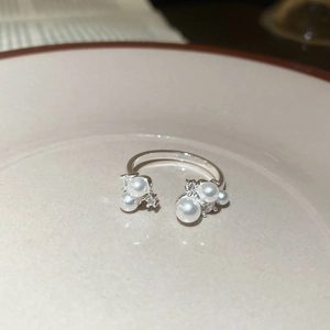 Detail of elegant open ring with white pearls and zircons on a beige ceramic plate