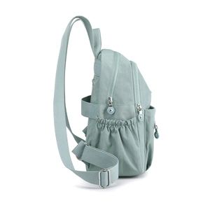 Detail view of light green nylon backpack side pocket and adjustable metal buckle