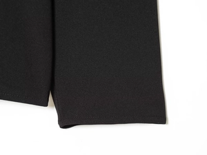 Nahaufnahme der schwarzen Textil-Stoffstruktur und der feinen Nähtechnik am Saum des Tops