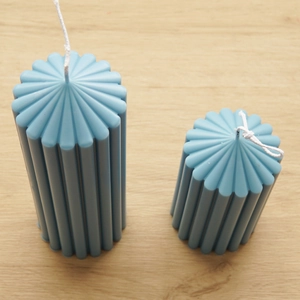 Top view of two light blue ribbed cylindrical scented candles on light wood surface