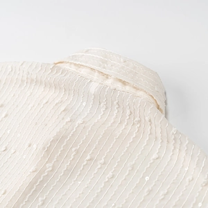 Detail of the cream textured neckline with subtle sequins and striped pattern fabric