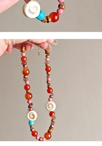 Macro detail of agate beads and shell pendant on ethnic style stainless steel necklace