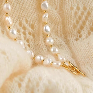 Detailed view of baroque pearl necklace with gold beads and a toggle clasp closure