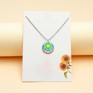 Detail view of silver sunflower necklace with turquoise petals on a quote display card