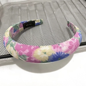 Detail of floral printed fabric headband with a black Hand Made label on a metal rack