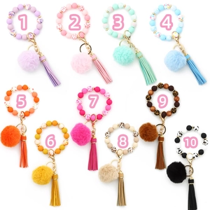 Flat lay of colorful silicone bead keychains with faux fur pom poms and leather tassels