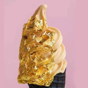 Macro shot of edible gold foil flakes decorating a chocolate ice cream in a black waffle cone
