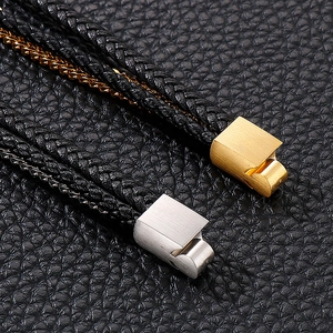 Close-up of multi-layer black braided leather bracelet with gold and silver magnetic clasps