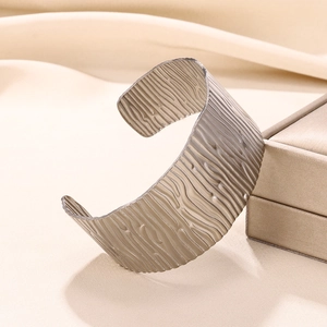 Macro shot of wide open bangle featuring unique bark texture and champagne silver finish