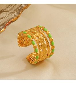 Detail view of a vintage gold-plated ring with green enamel dots and floral texture