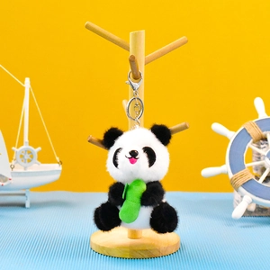 Lindo llavero de panda de peluche con bambú en un soporte de madera para joyas