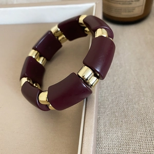Close-up of burgundy tubular acrylic beads bracelet with polished gold metal spacers