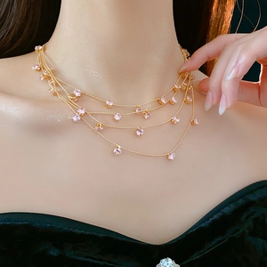 Gros plan d'un collier doré multicouche avec zircons roses sur un cou féminin
