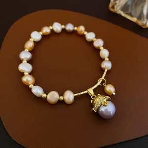 Detail of freshwater pearl bracelet with a gold lucky cat charm and zircon inlay