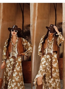 Detail of a brown leather western belt paired with an embroidered vest and floral dress