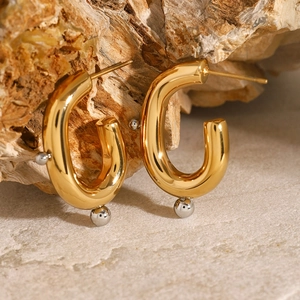 Macro view of gold and silver plated stainless steel U-shaped earrings on stone